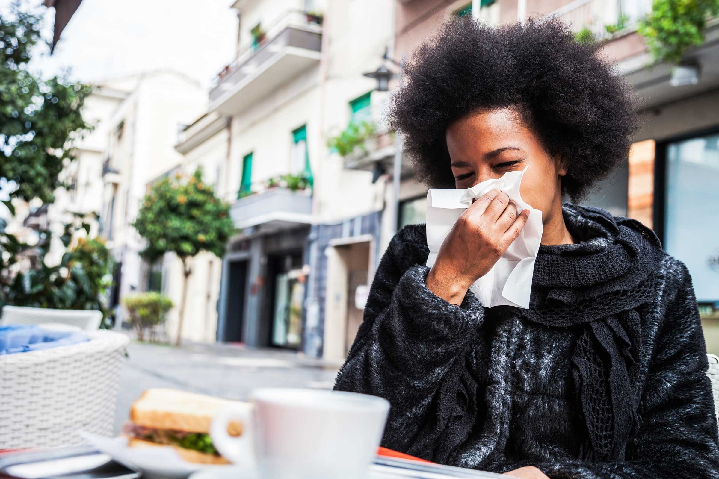 African American woman sneezing into a tissue