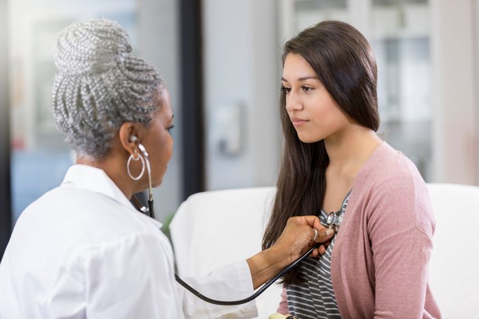 doctor listening to young girl's heart with stethoscope