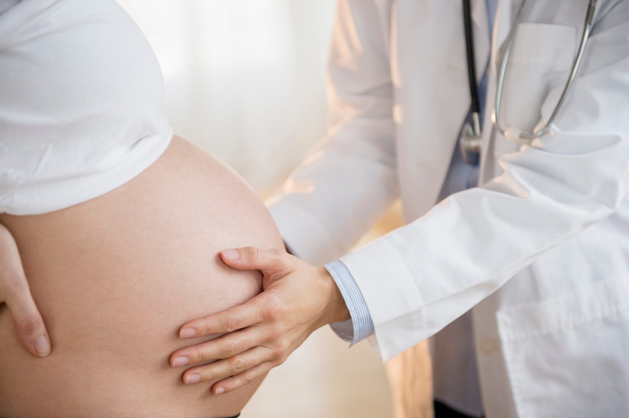 doctor examining pregnant belly close up