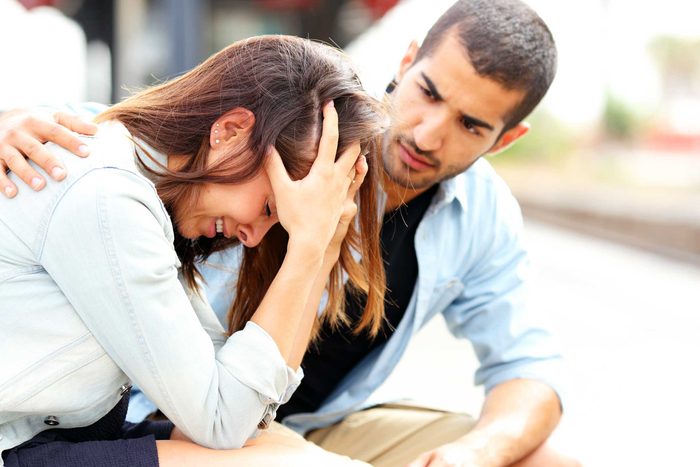 man with arm around upset woman