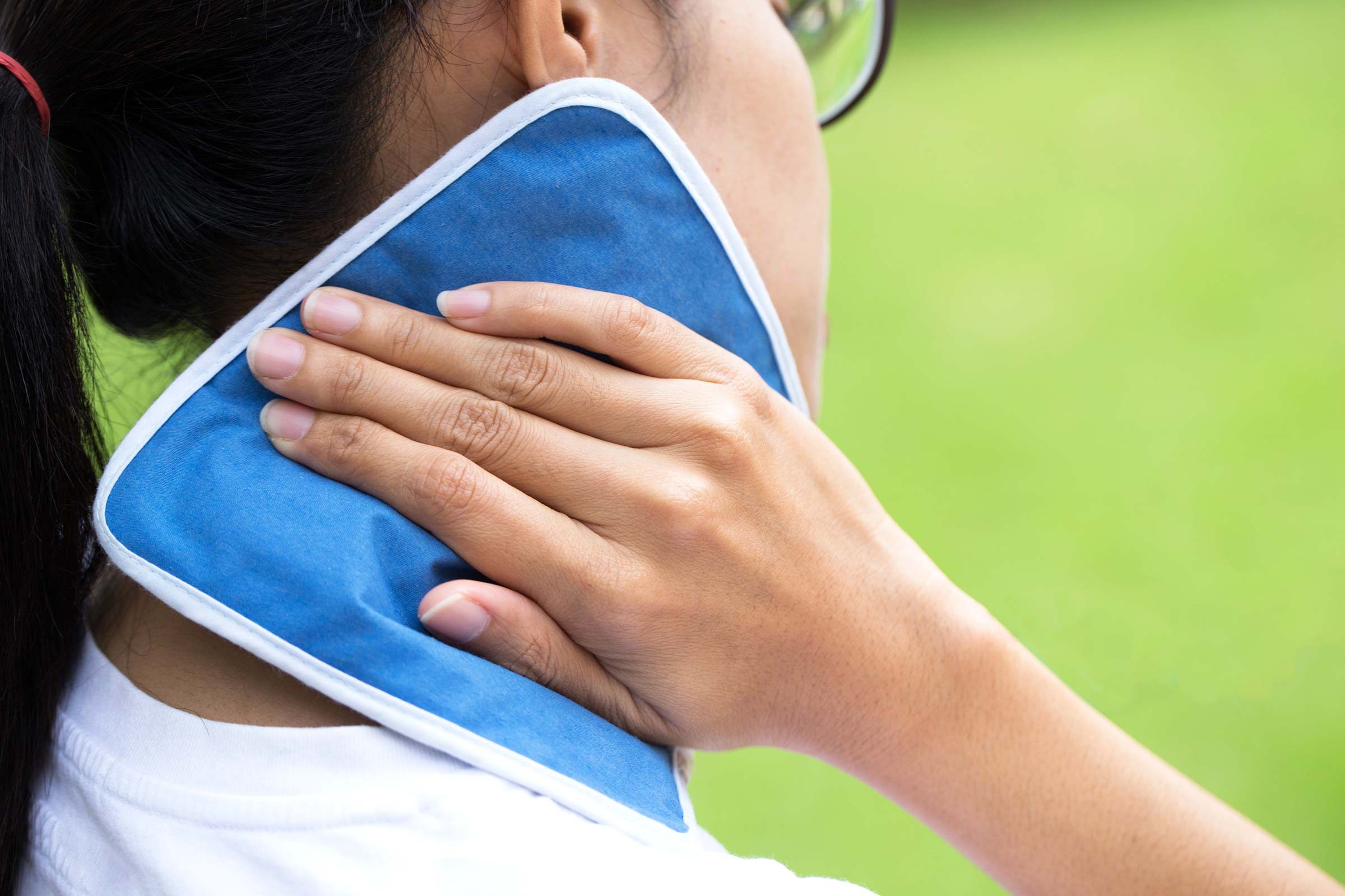 woman holding compress to neck