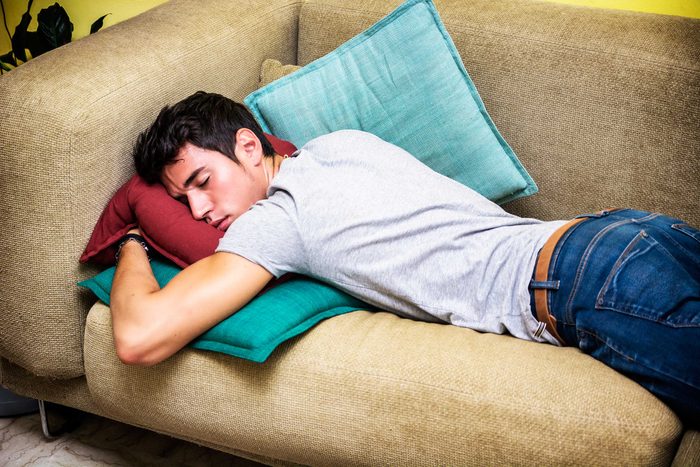 man sleeping face-down on couch