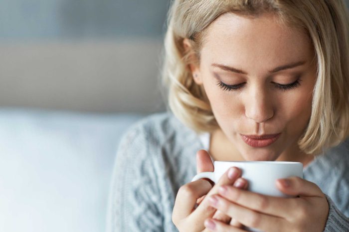 woman blowing on a cup of coffee