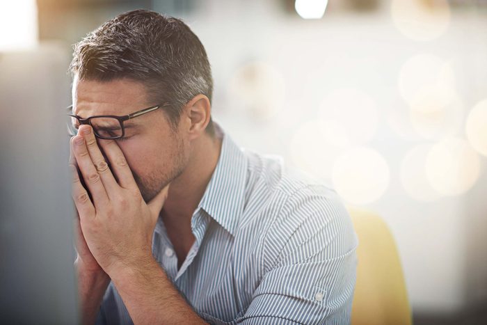 man in pain pressing his fingers against the bridge of his nose