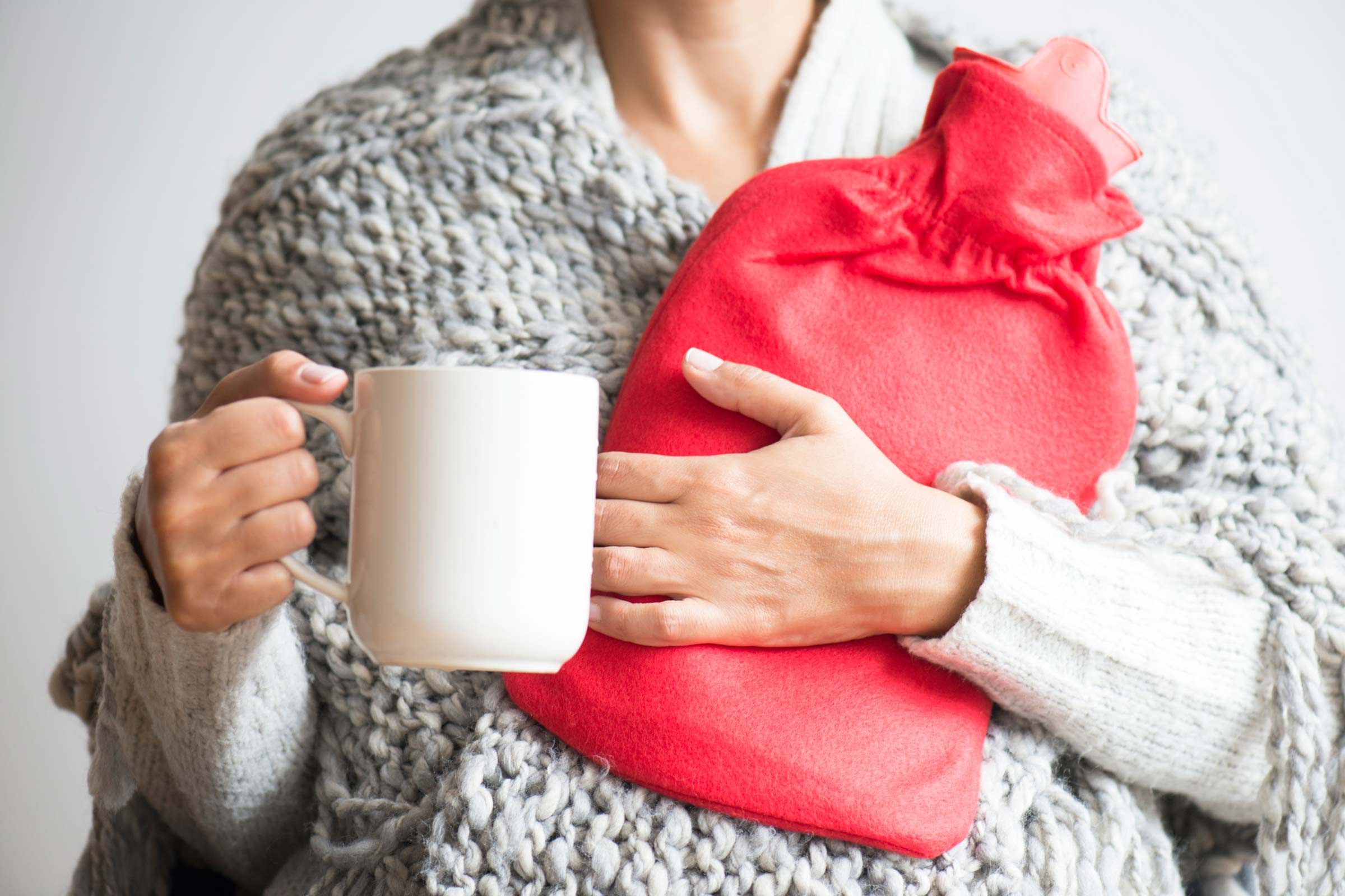 Woman with mug and hot-water bladder
