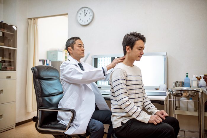 chiropractor examining patient's neck and back