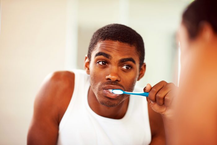 man brushing his teeth in a mirror