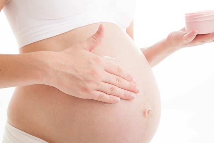 pregnant woman applying cream on belly