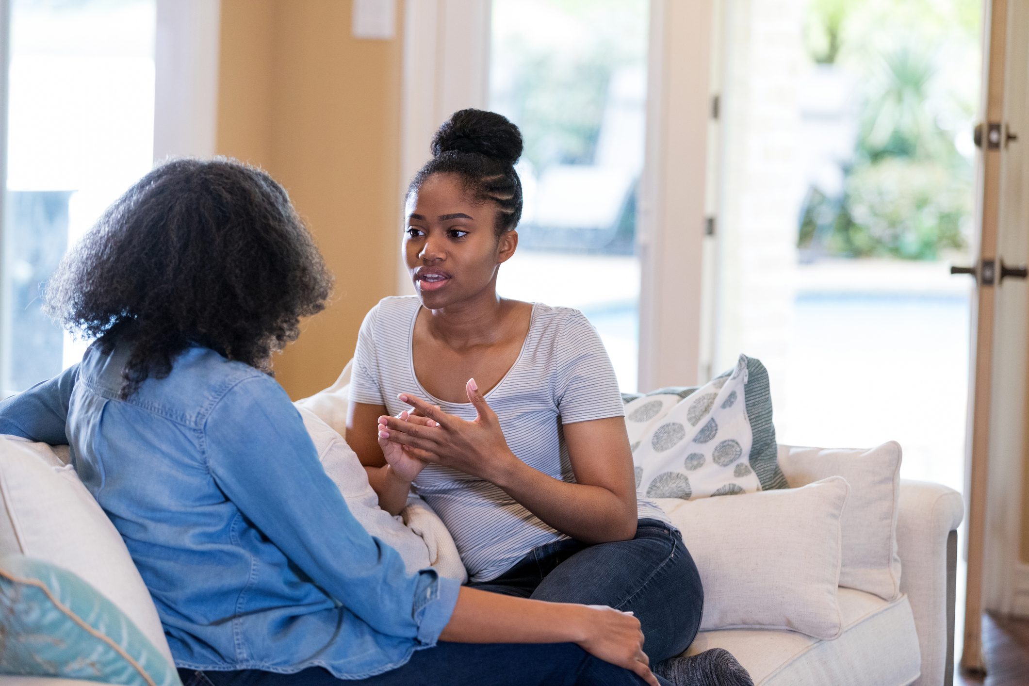 young woman talks with her mother at home on the couch