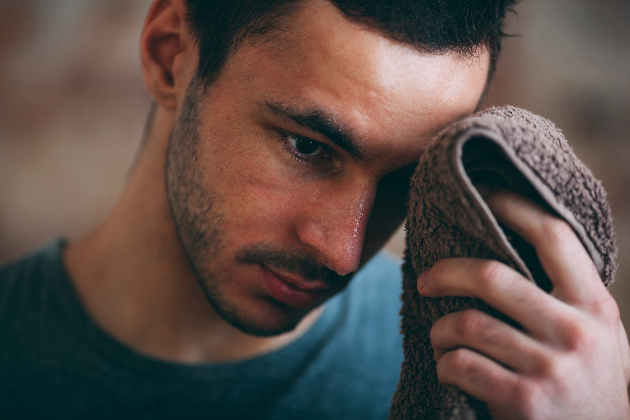 man wiping sweat with towel during workout