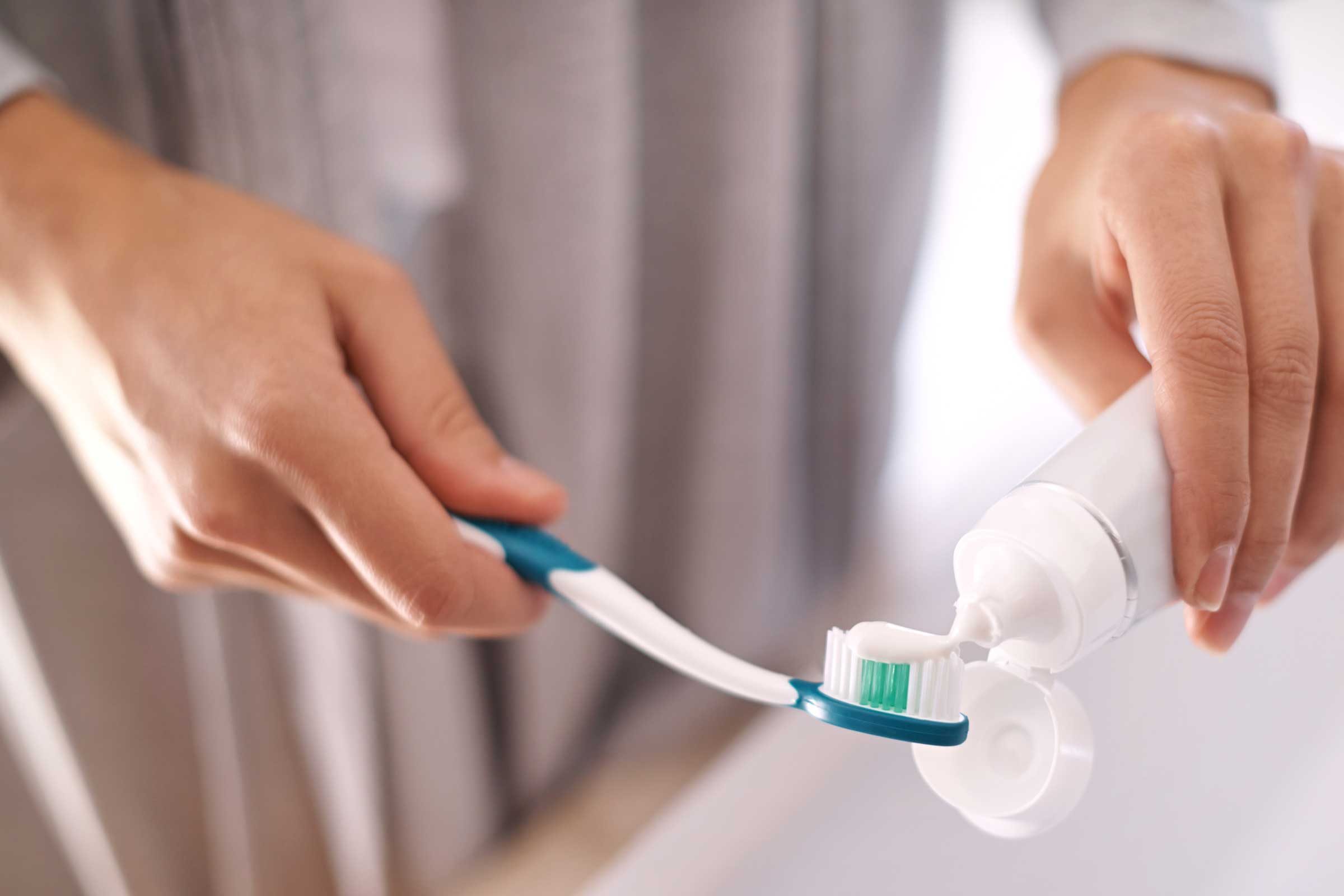woman squeezing toothpaste on toothbrush