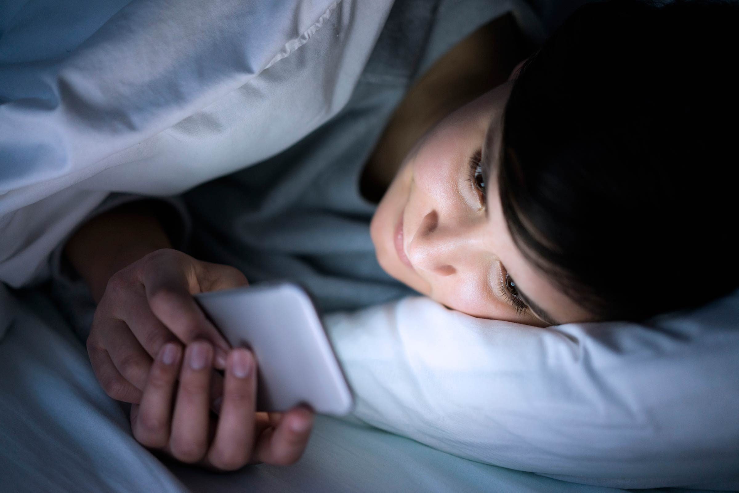 woman reading smartphone in bed