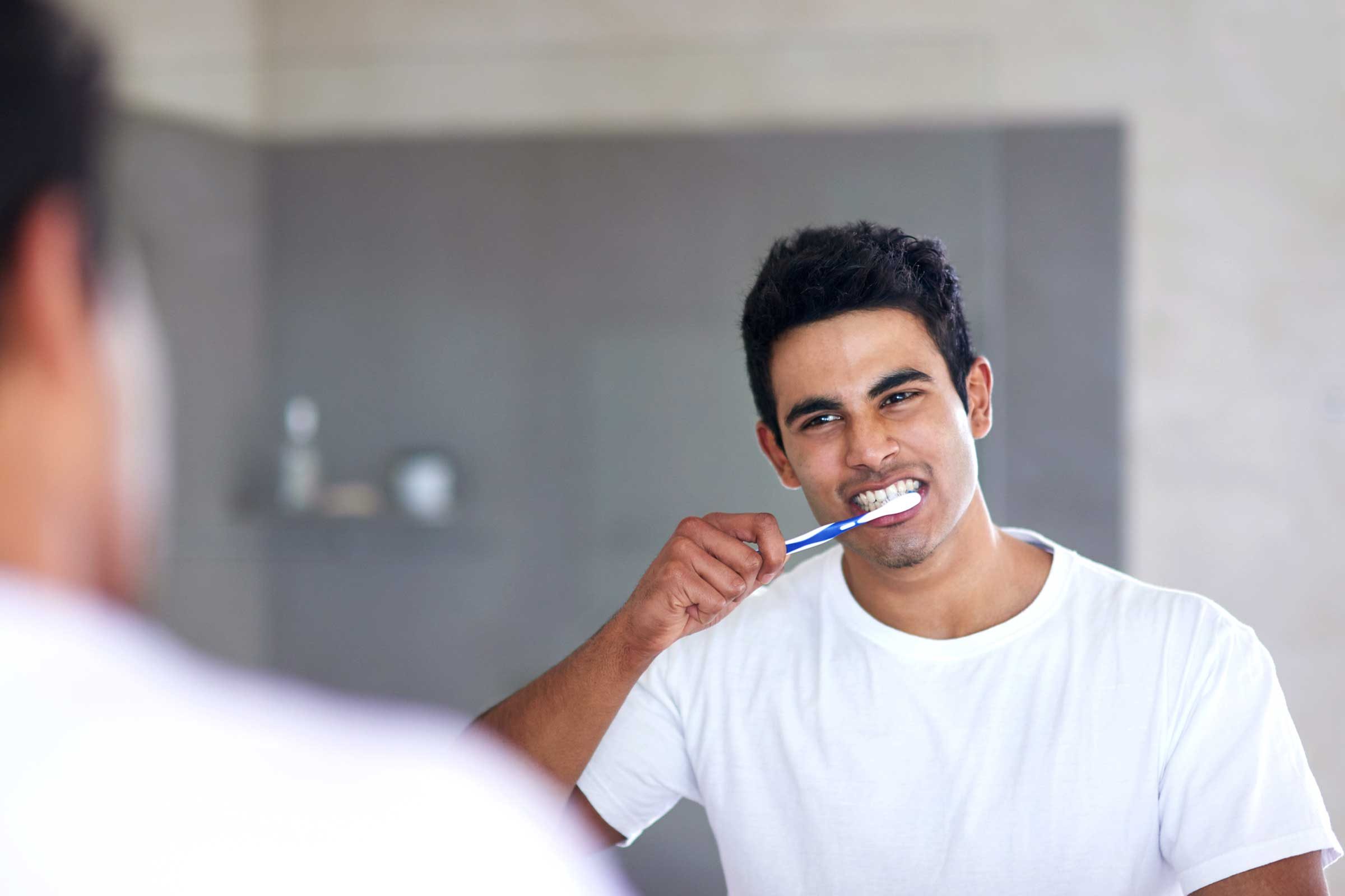 man brushing his teeth in front of a mirror