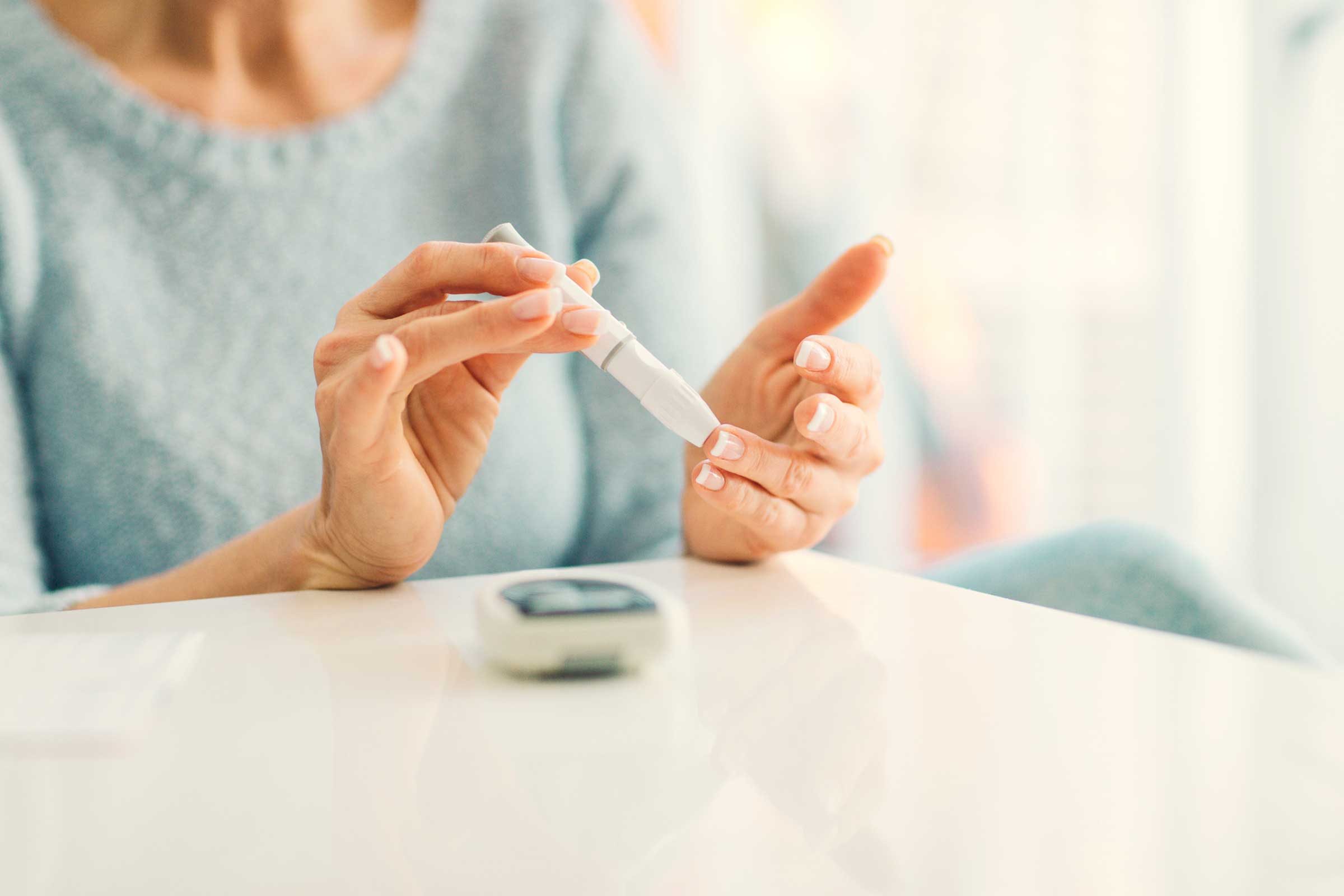 woman checking her blood sugar with a finger-prick device