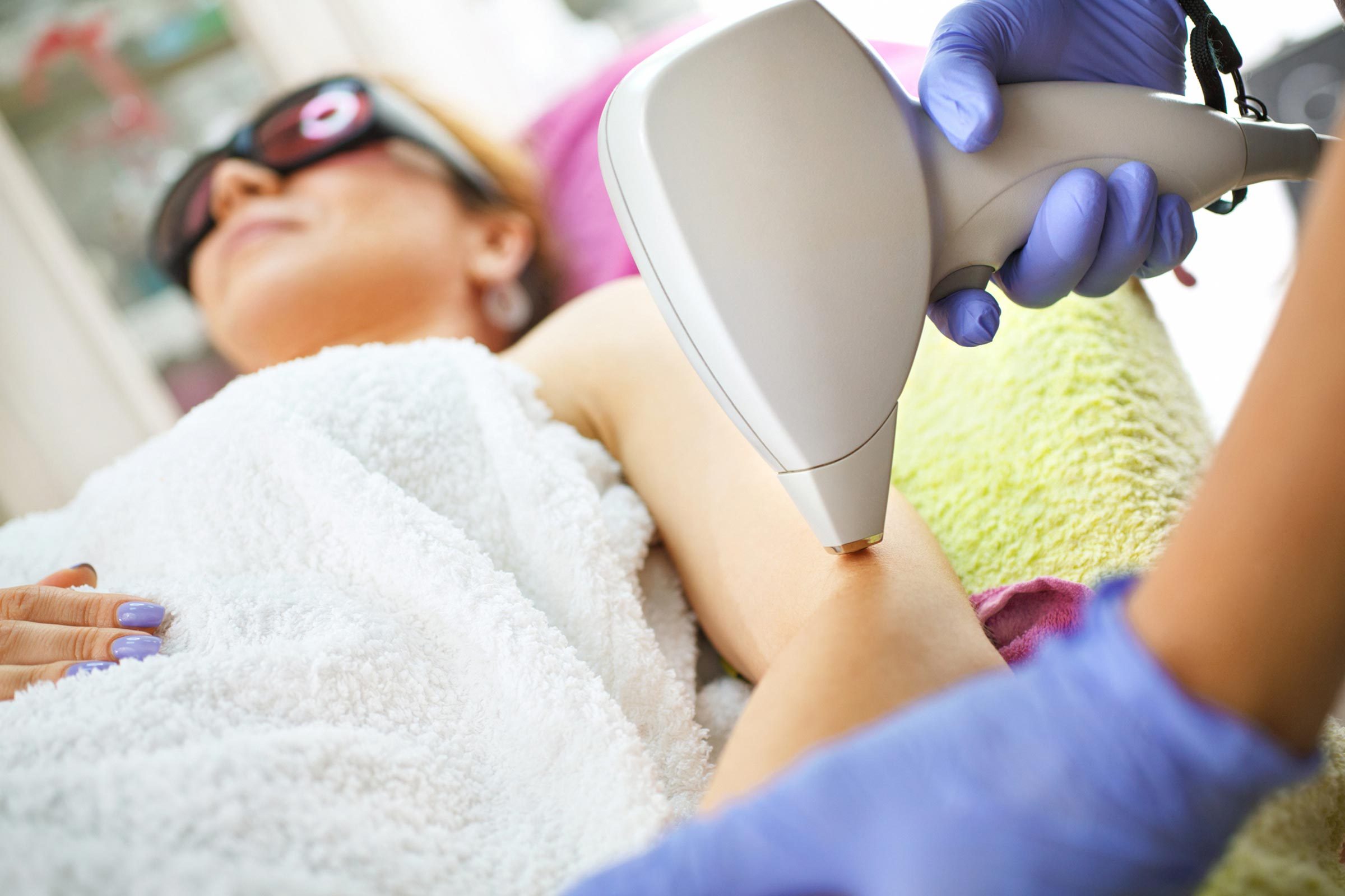 Women in medical office undergoing laser procedure on her arm.