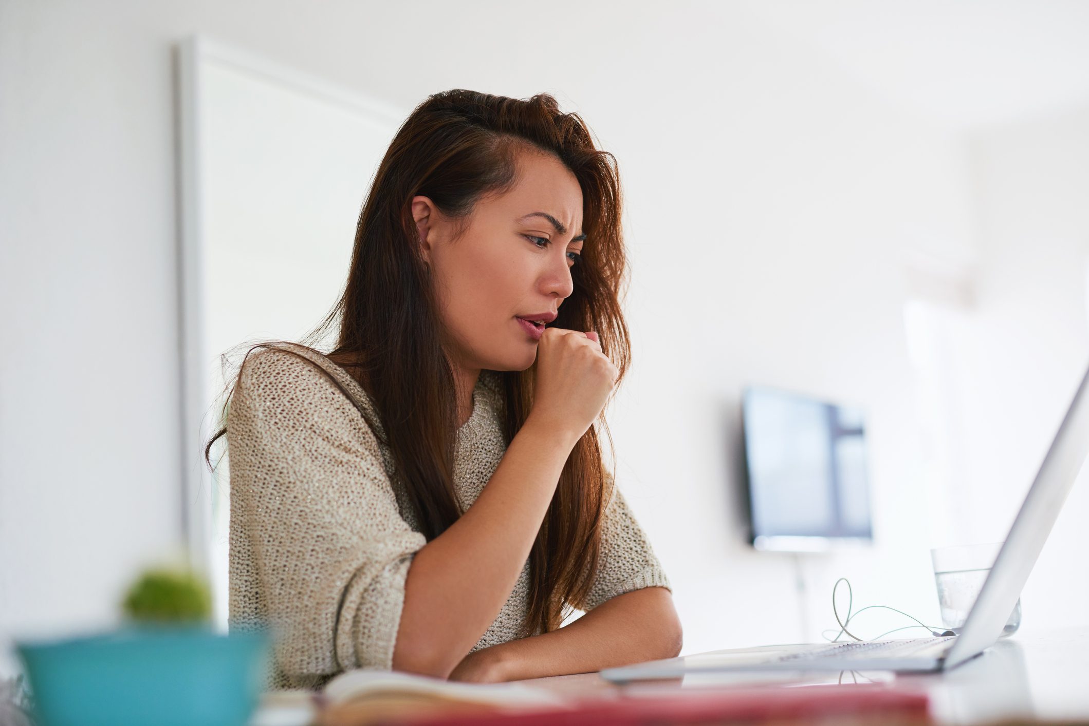 young woman coughing while working from home