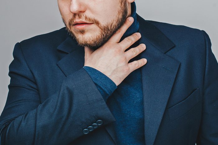 man in blue suit holding throat