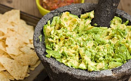 guacamole in a bowl with chips in the background