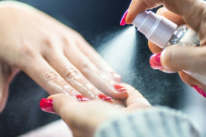 manicurist spraying a substance on customer's nails