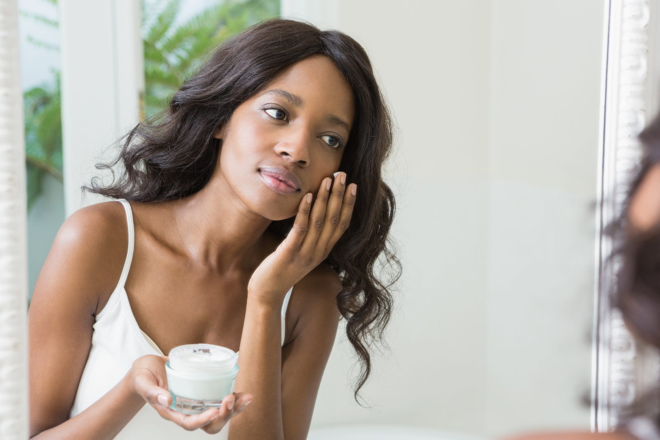 young woman applying moisturizer to face