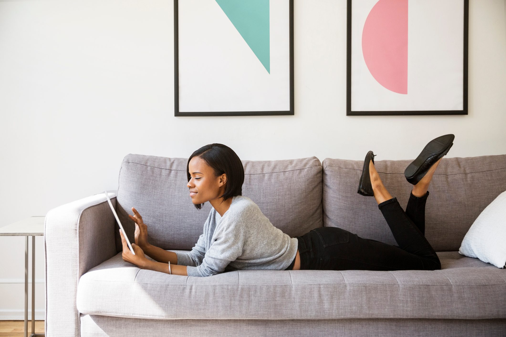 woman laying on couch looking at tablet