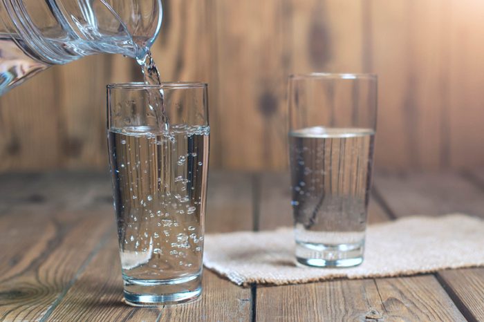 Pitcher pouring water into a glass on a wooden table