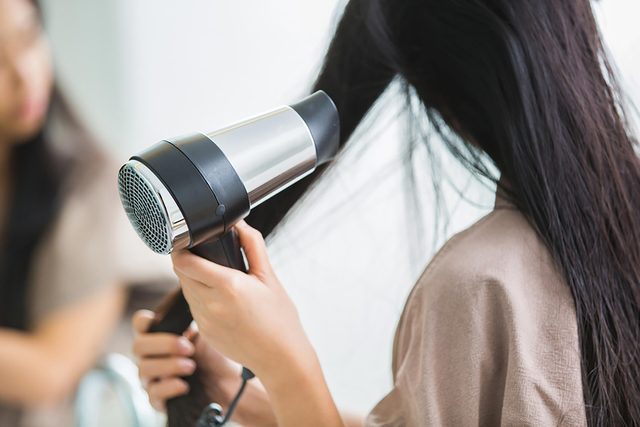 woman drying hair with blow-dryer