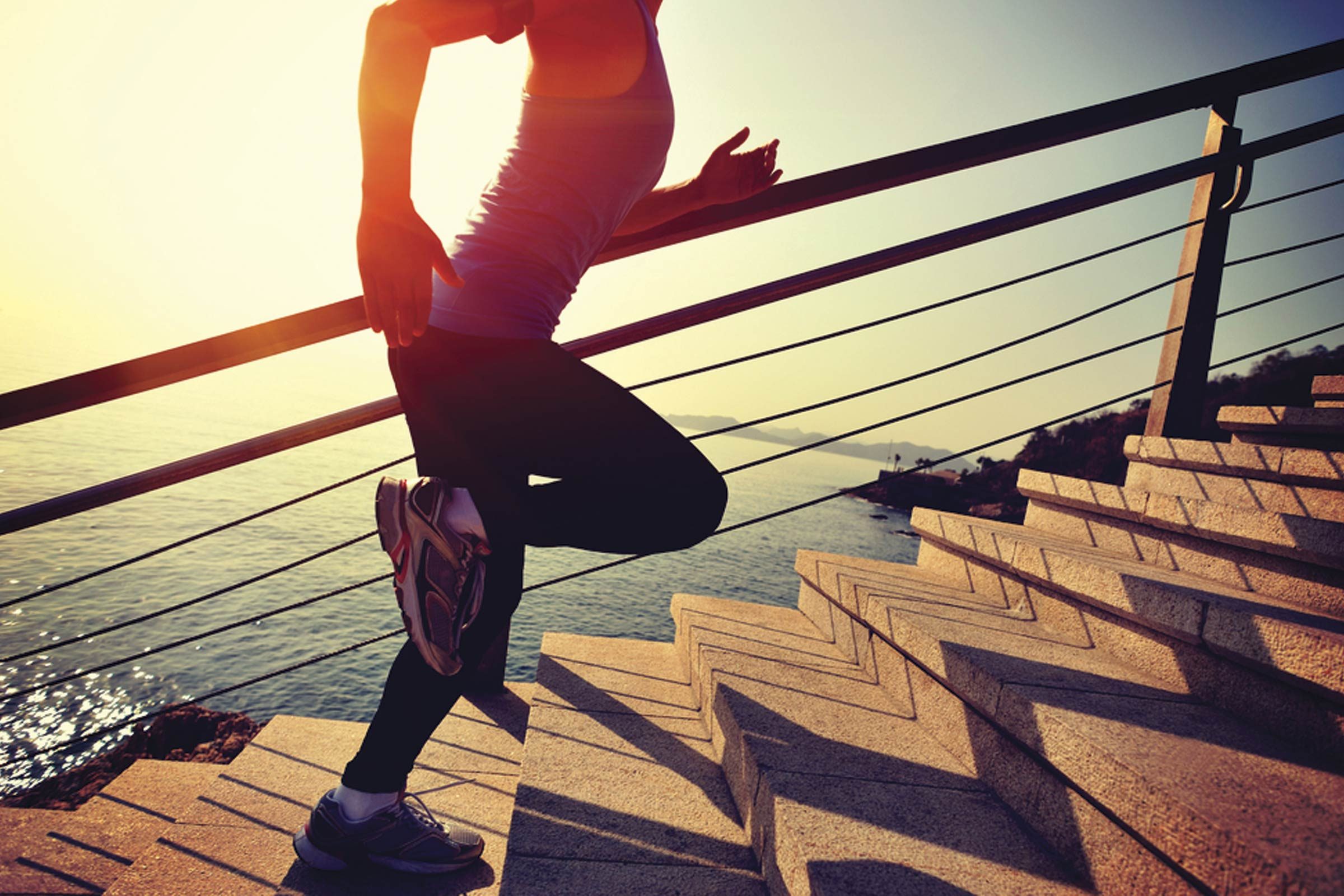 person running up outdoor stairs, ocean in background