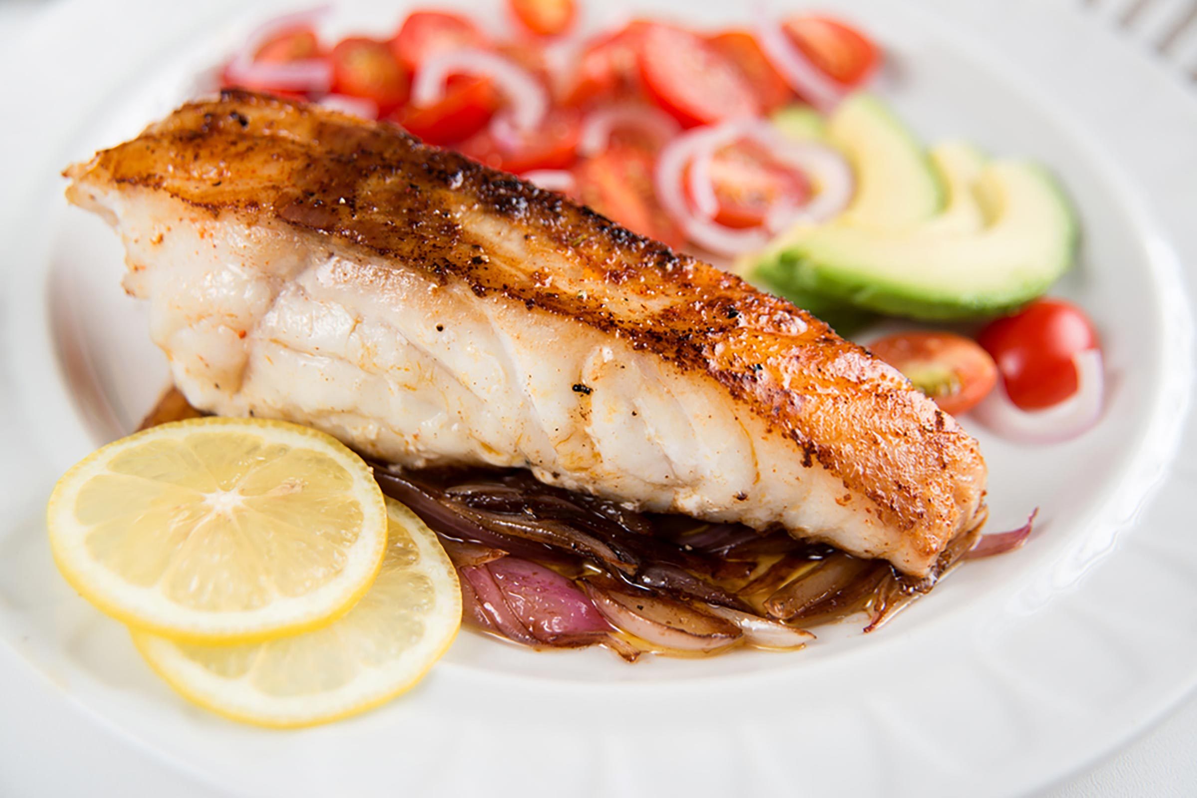 plate of cooked white fish filet with vegetables 