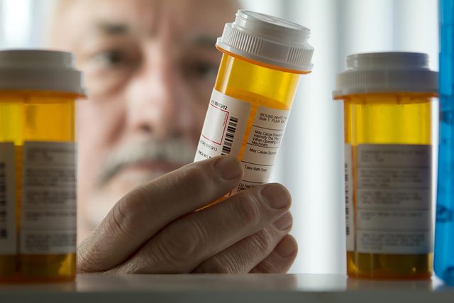 man looking at prescriptions in bottles