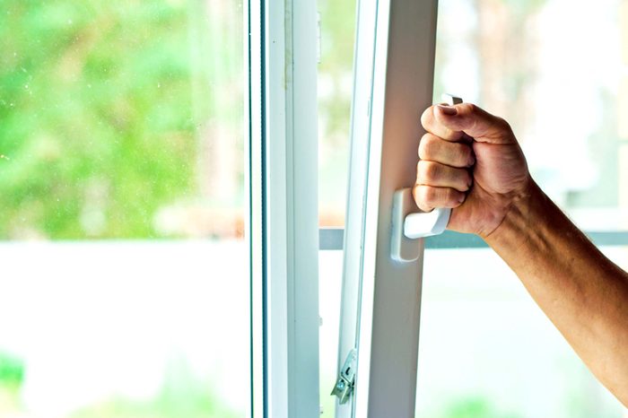 a hand pulling open a window