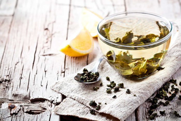 Cup of green tea with lemon on side