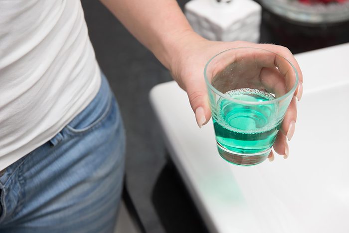 woman's hand holding glass of mouthwash