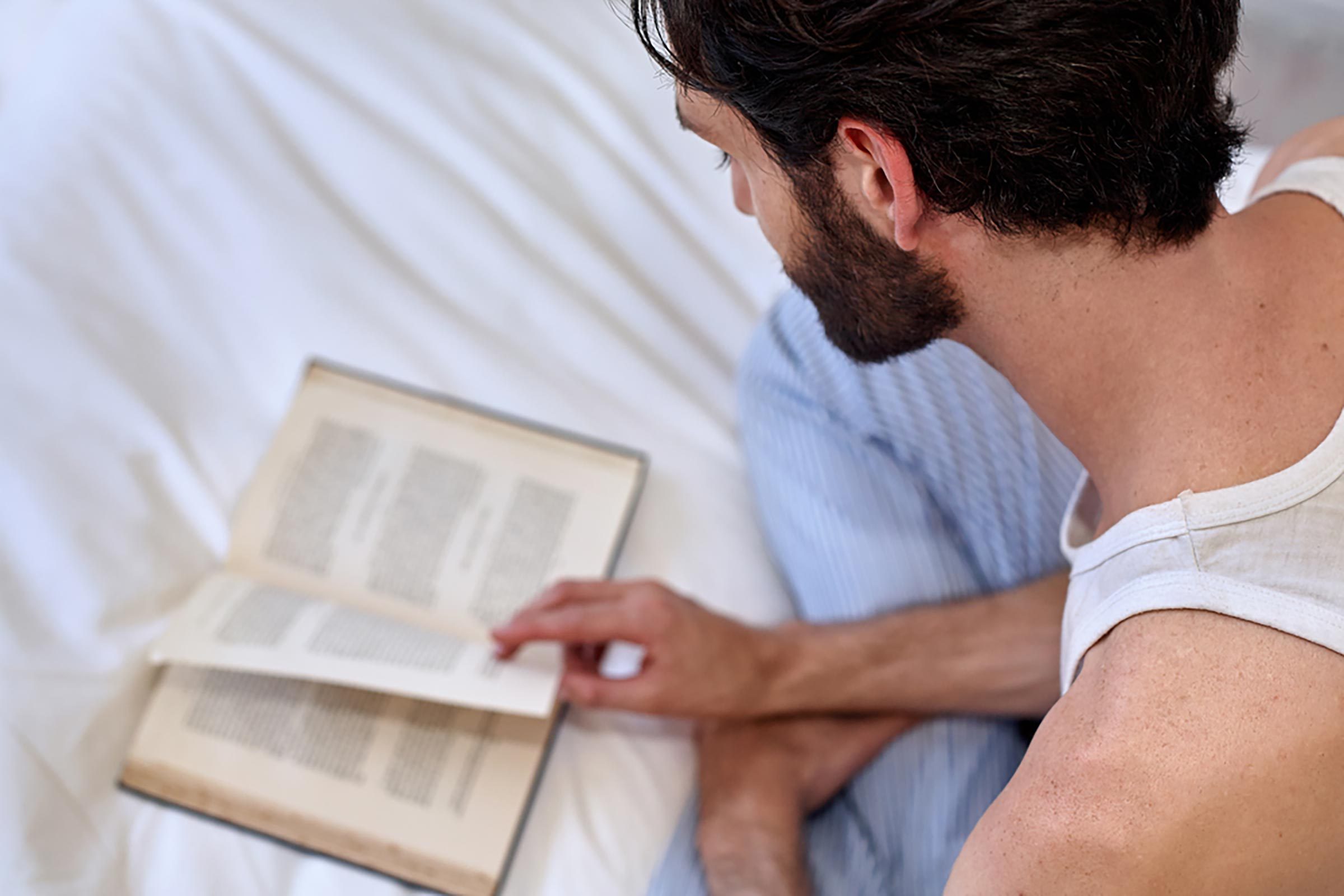 man reading a book in bed