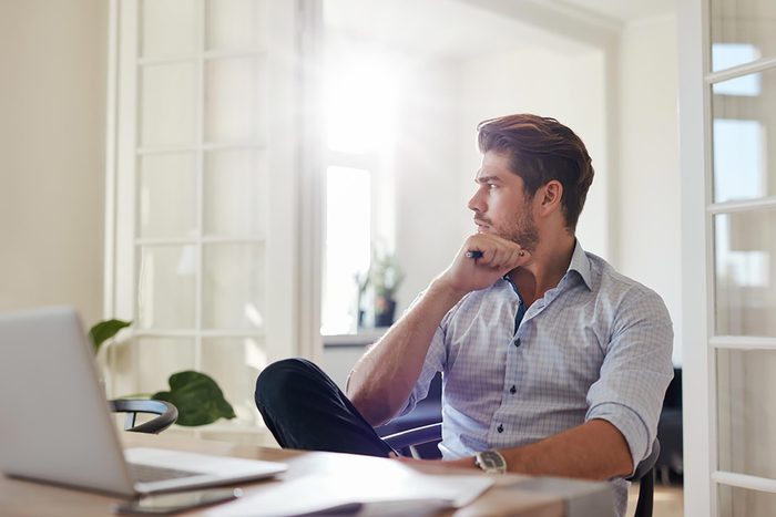 man looking out window while sitting at computer