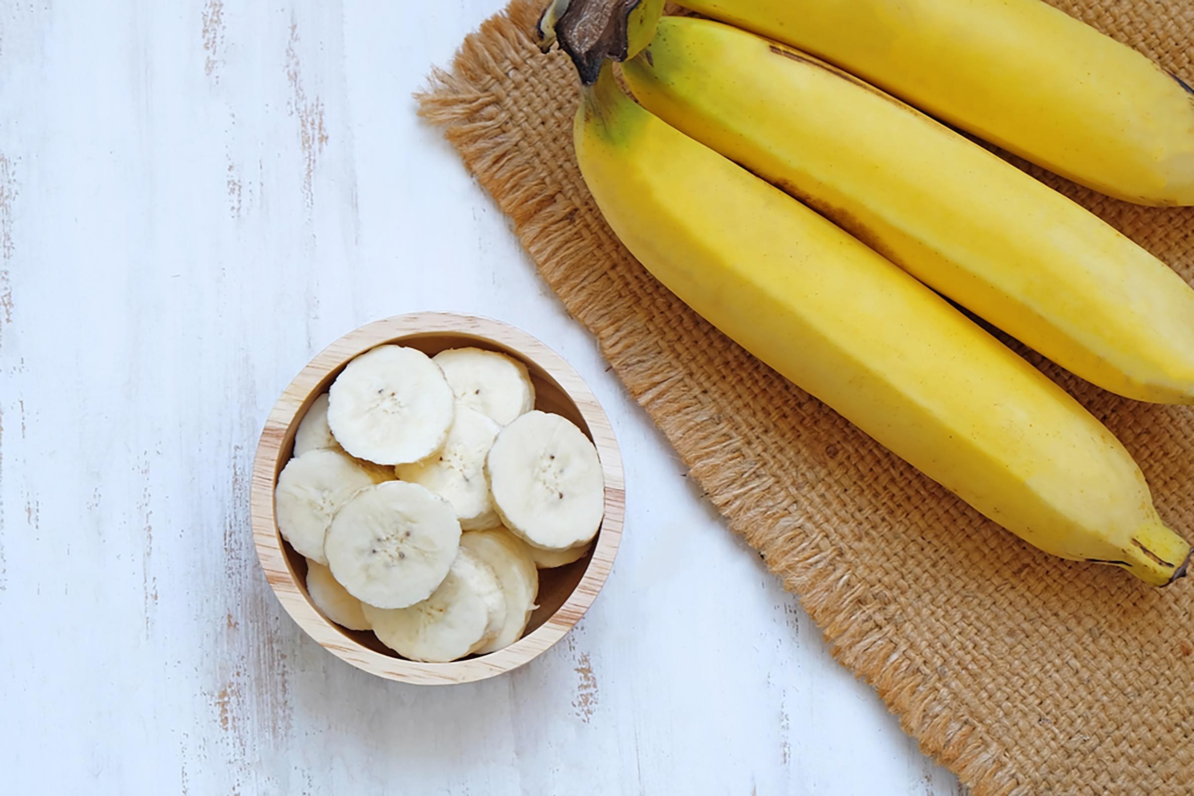 whole bananas on placemat next to small bowl of banana slices