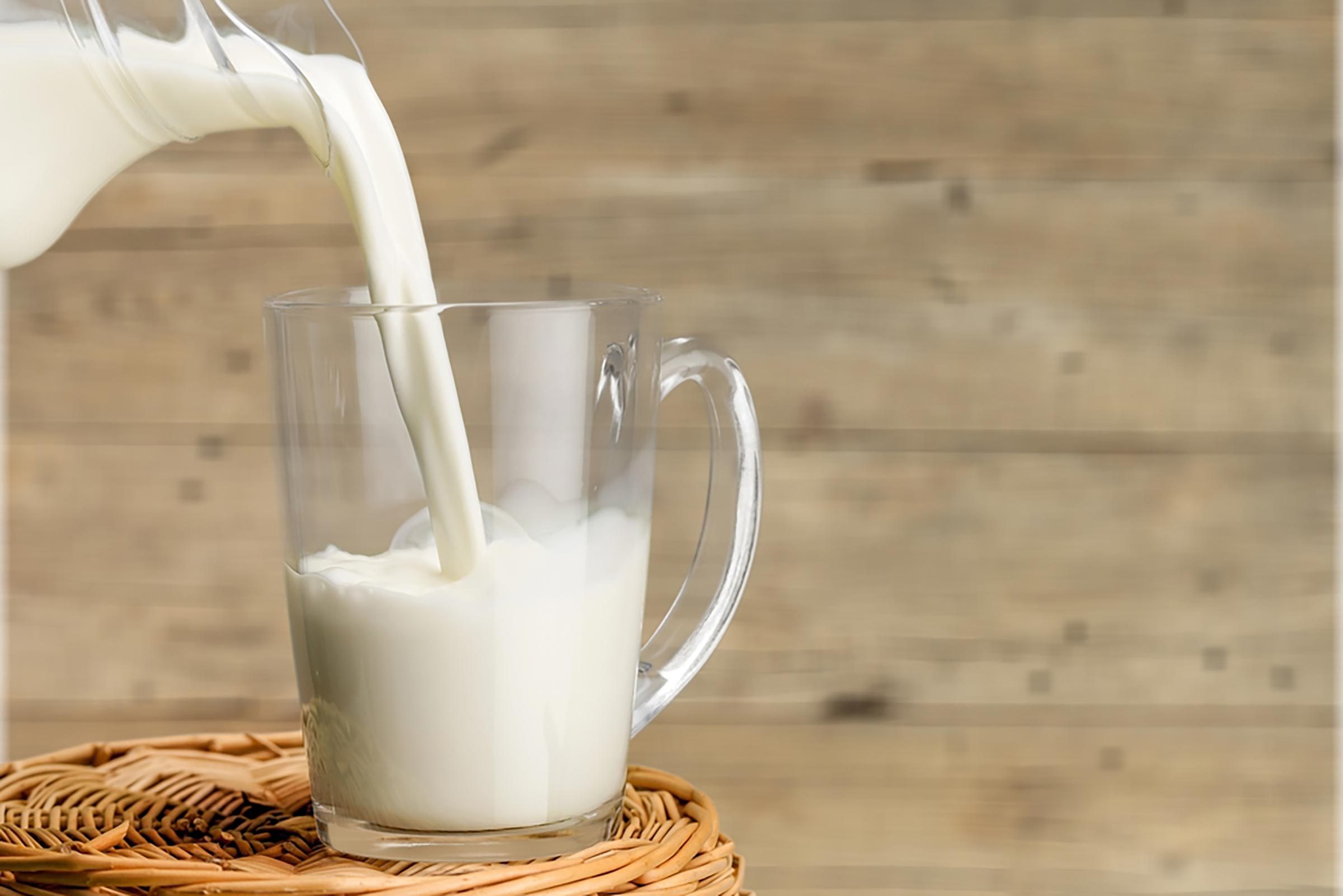 milk being poured in glass mug