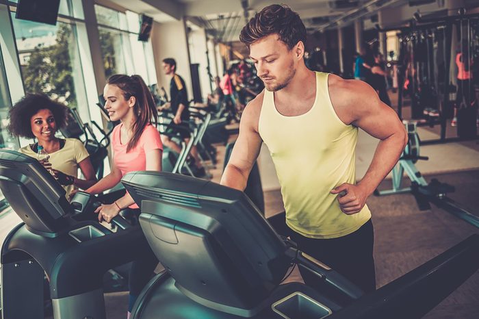Man working out at the gym on an elliptical.