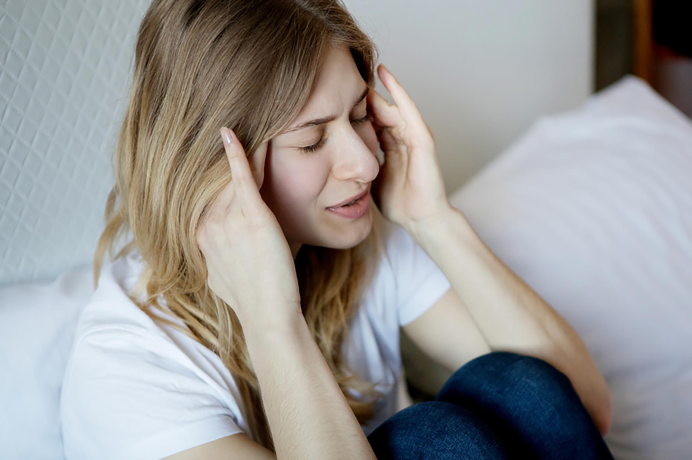 woman with headache, pressing hands to her temples