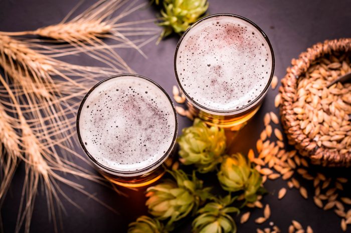 Top view of two glasses of beer surrounded by hops and wheat.