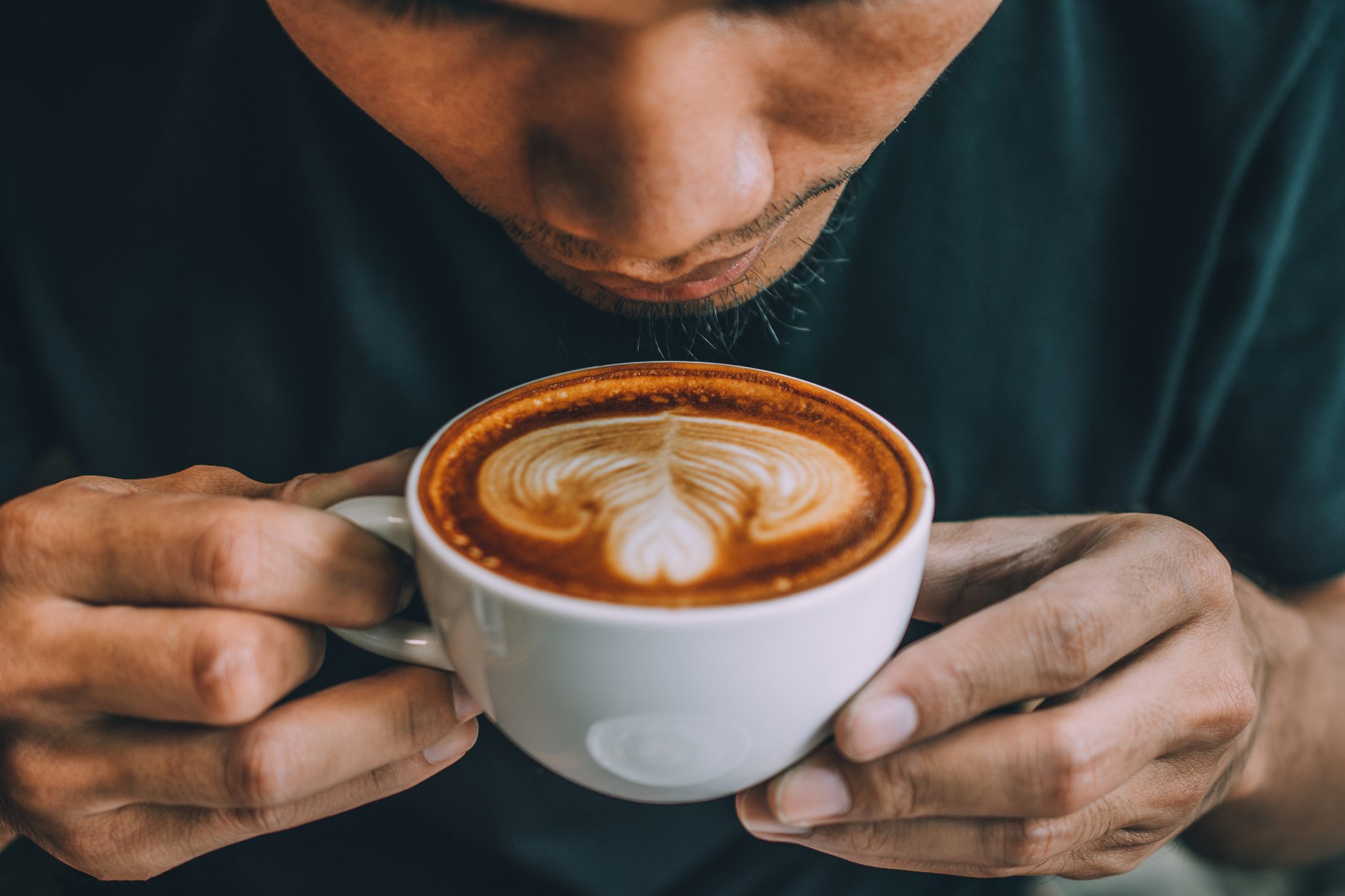 man blowing on cup of coffee