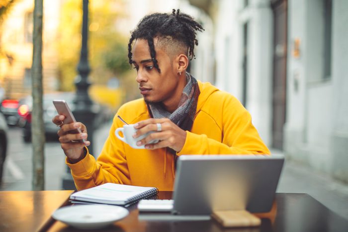 man sitting at cafe with laptop and cup of coffee
