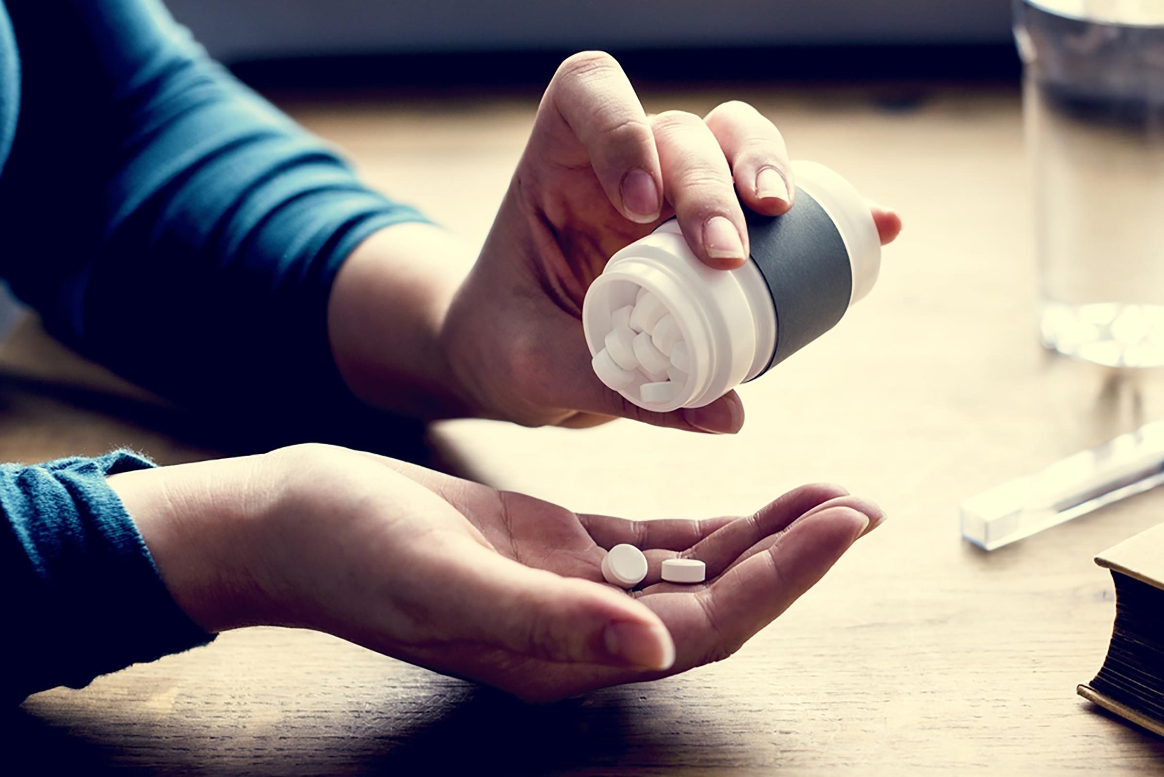 woman taking pills from pill bottle