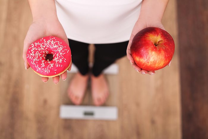 person holding apple and donut