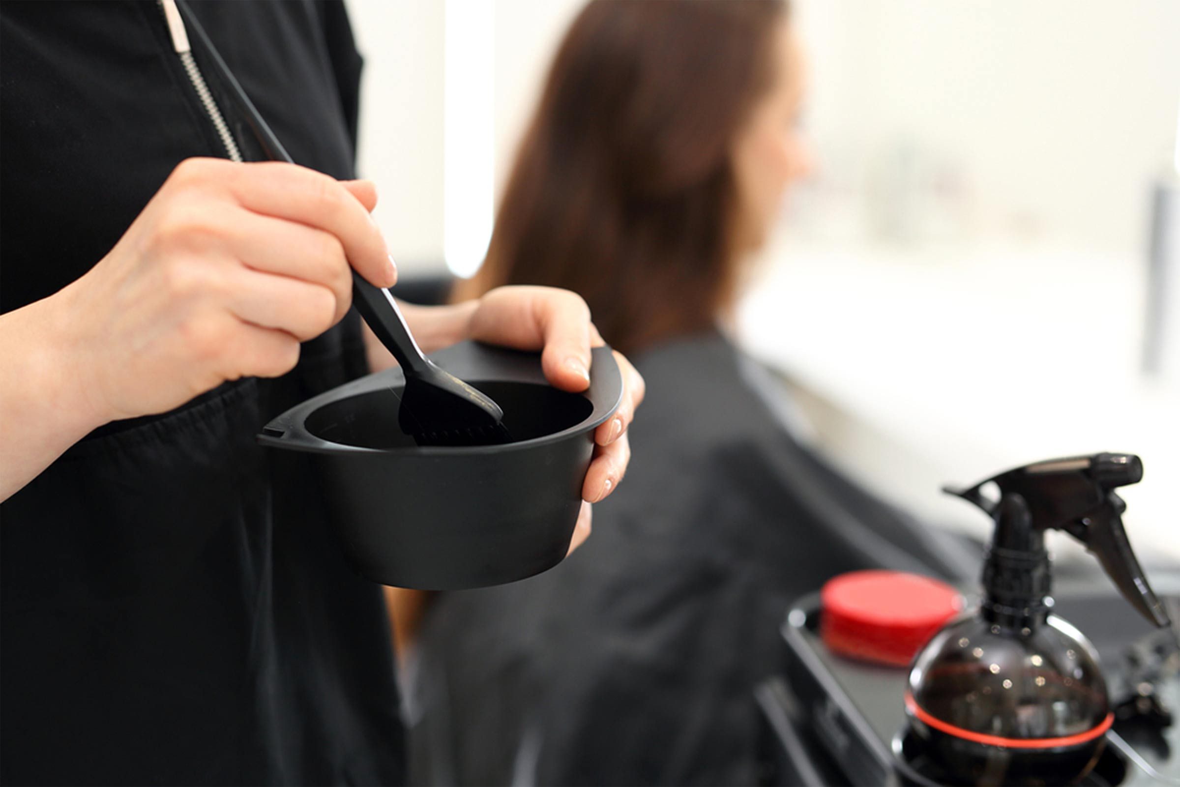 hair salon stylists mixing dye with girl in background