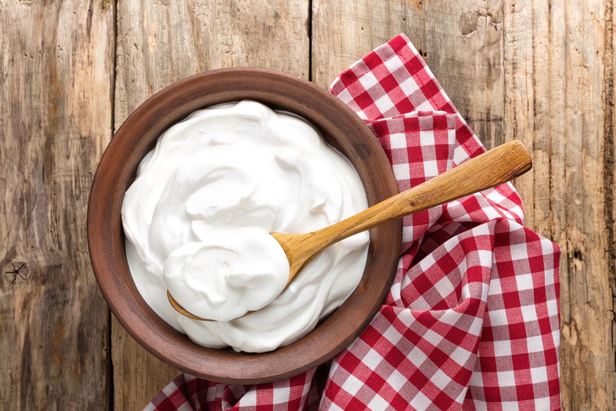 wooden bowl filled with yogurt with a wooden spoon