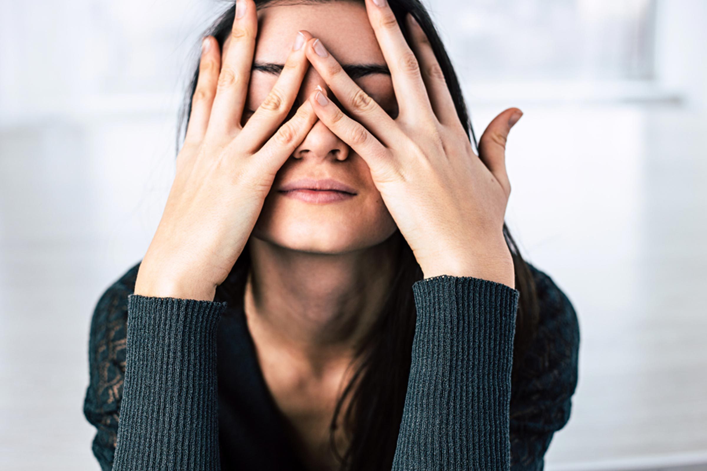 woman pressing her hands to her face