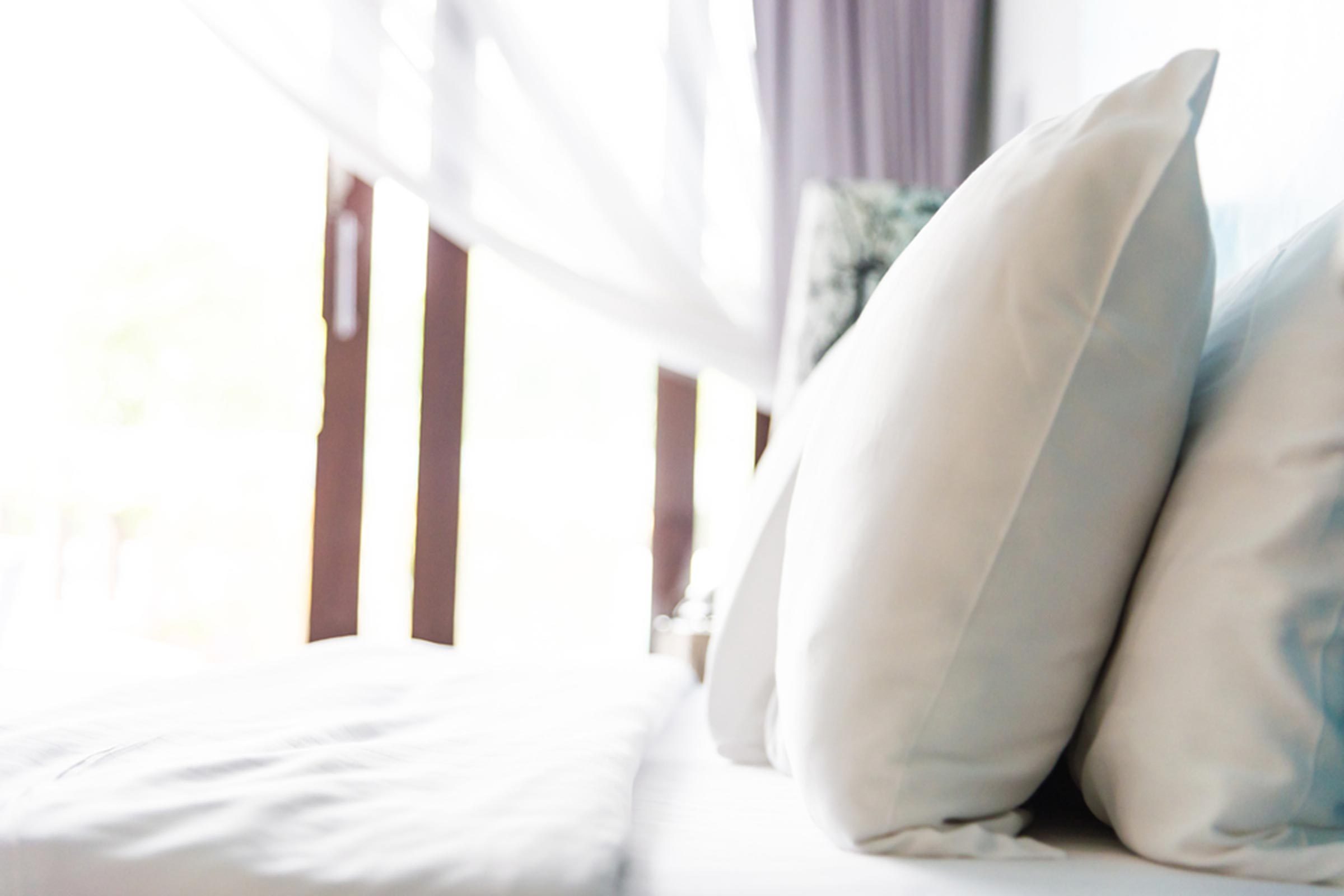 bed sheets and pillows in front of a window