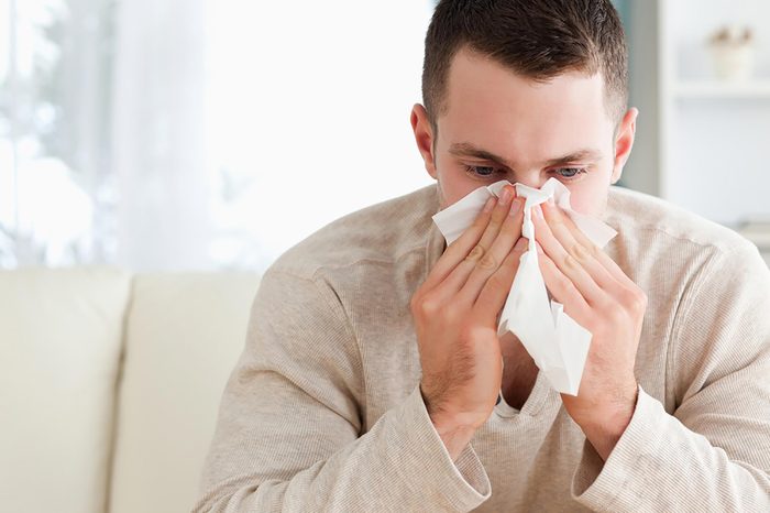 man sneezing into tissue