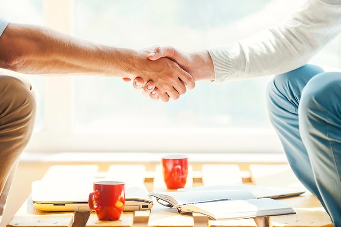 two people shaking hands over a table